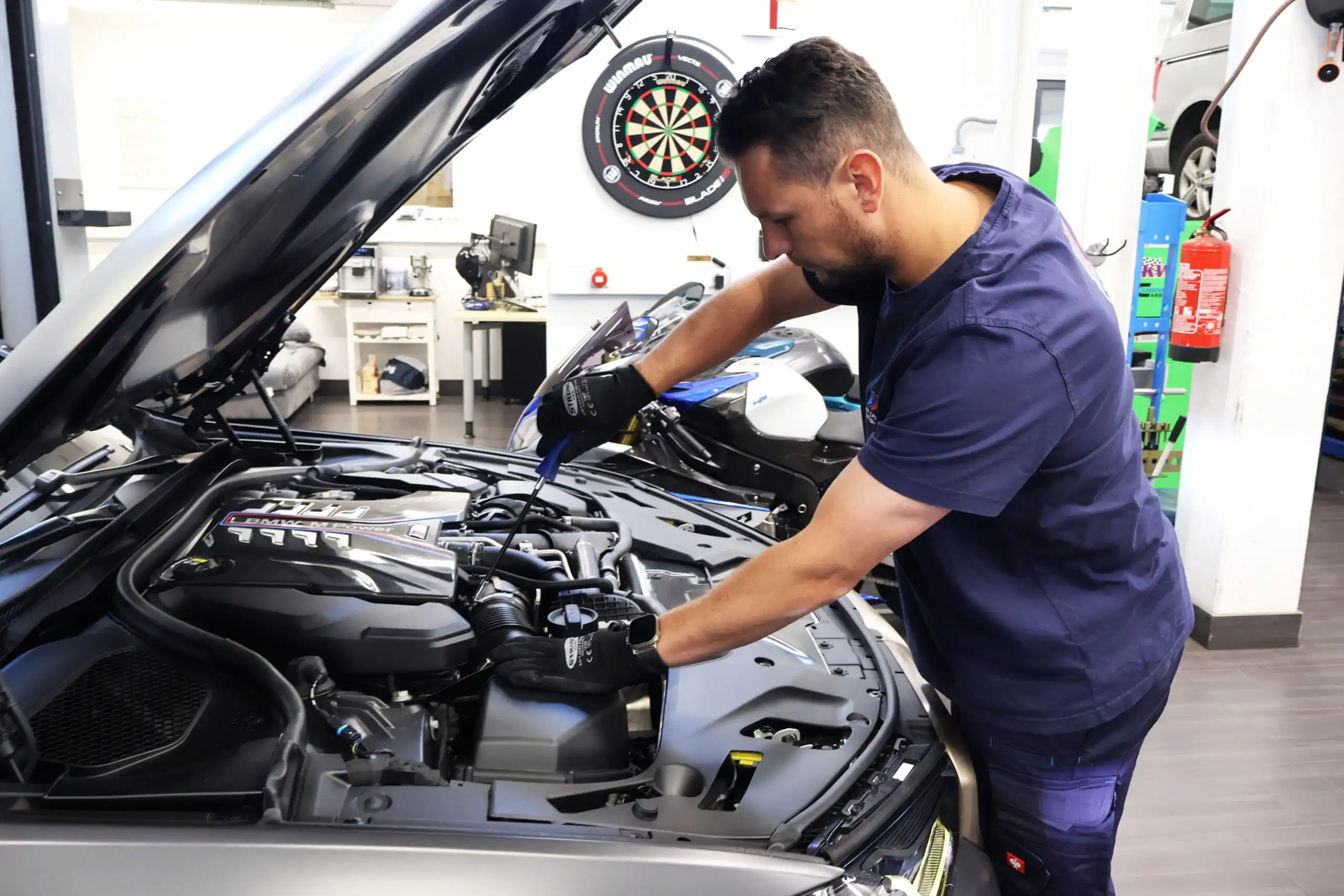 Inhaber von Hiller CarTech arbeitet am Motor eines Fahrzeugs in der eigenen Kfz-Werkstatt