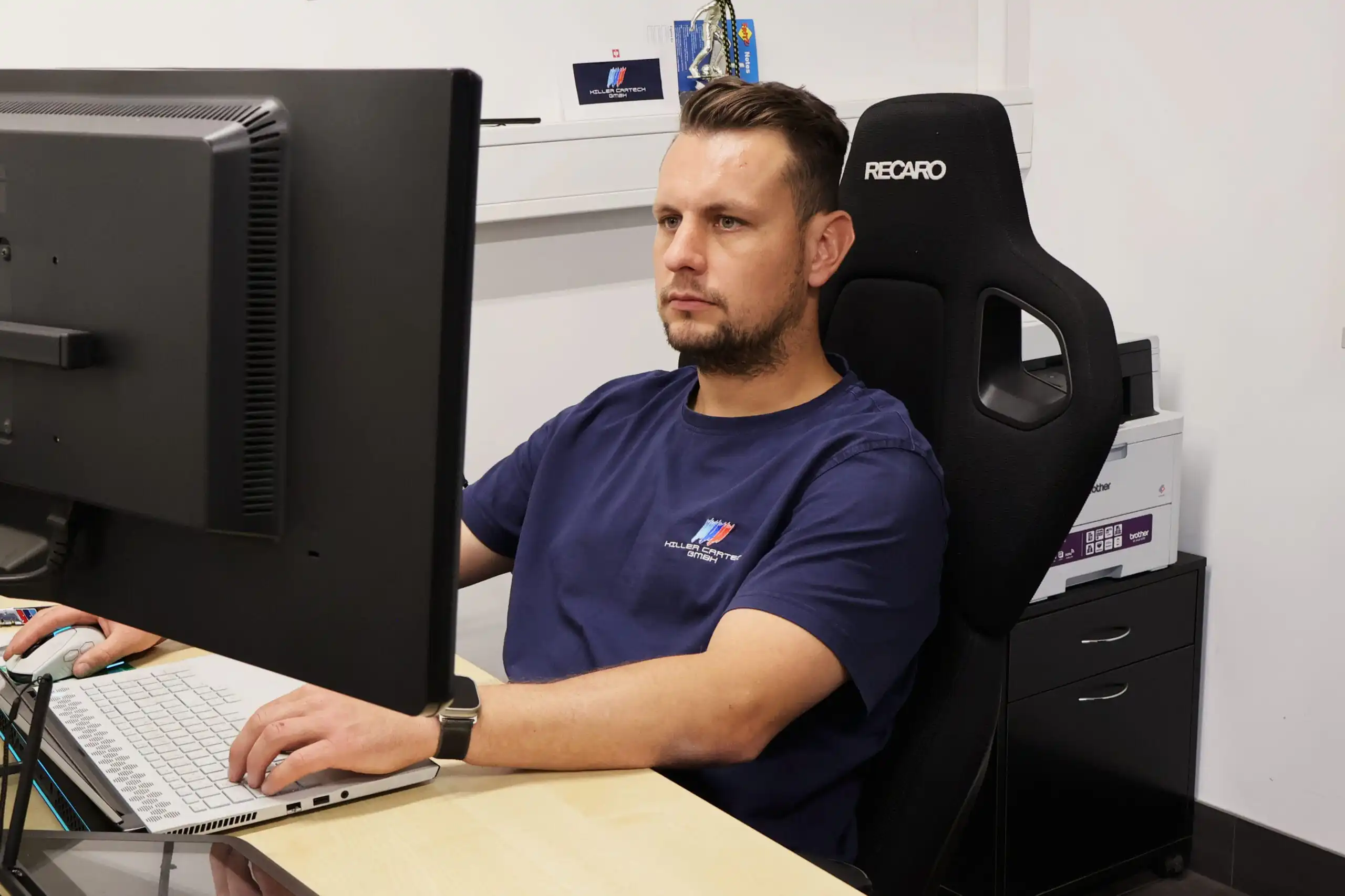 Inhaber von Hiller CarTech arbeitet am Computer an Fahrzeugdaten und Planung